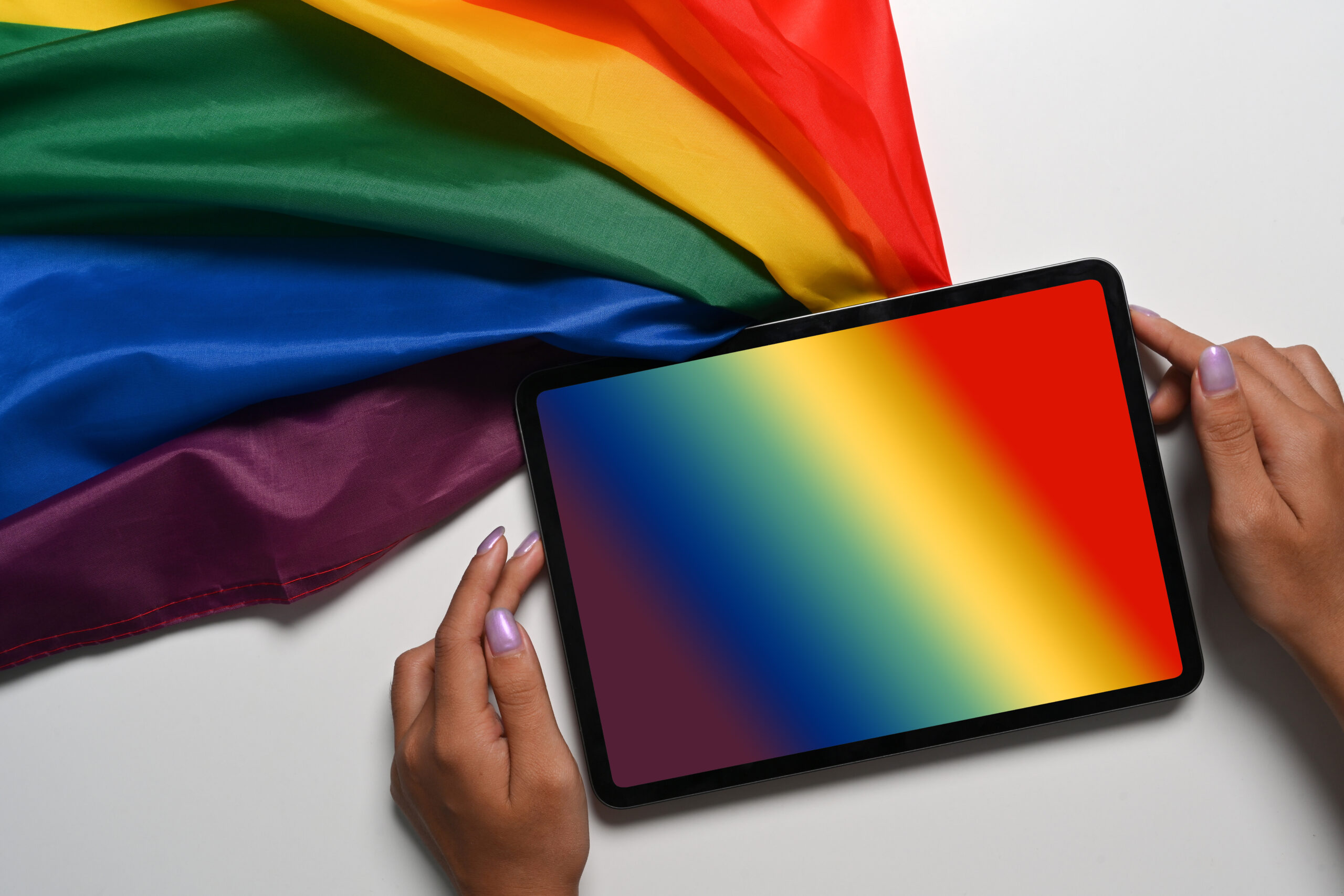Above view female holding digital tablet with rainbow flag on wh