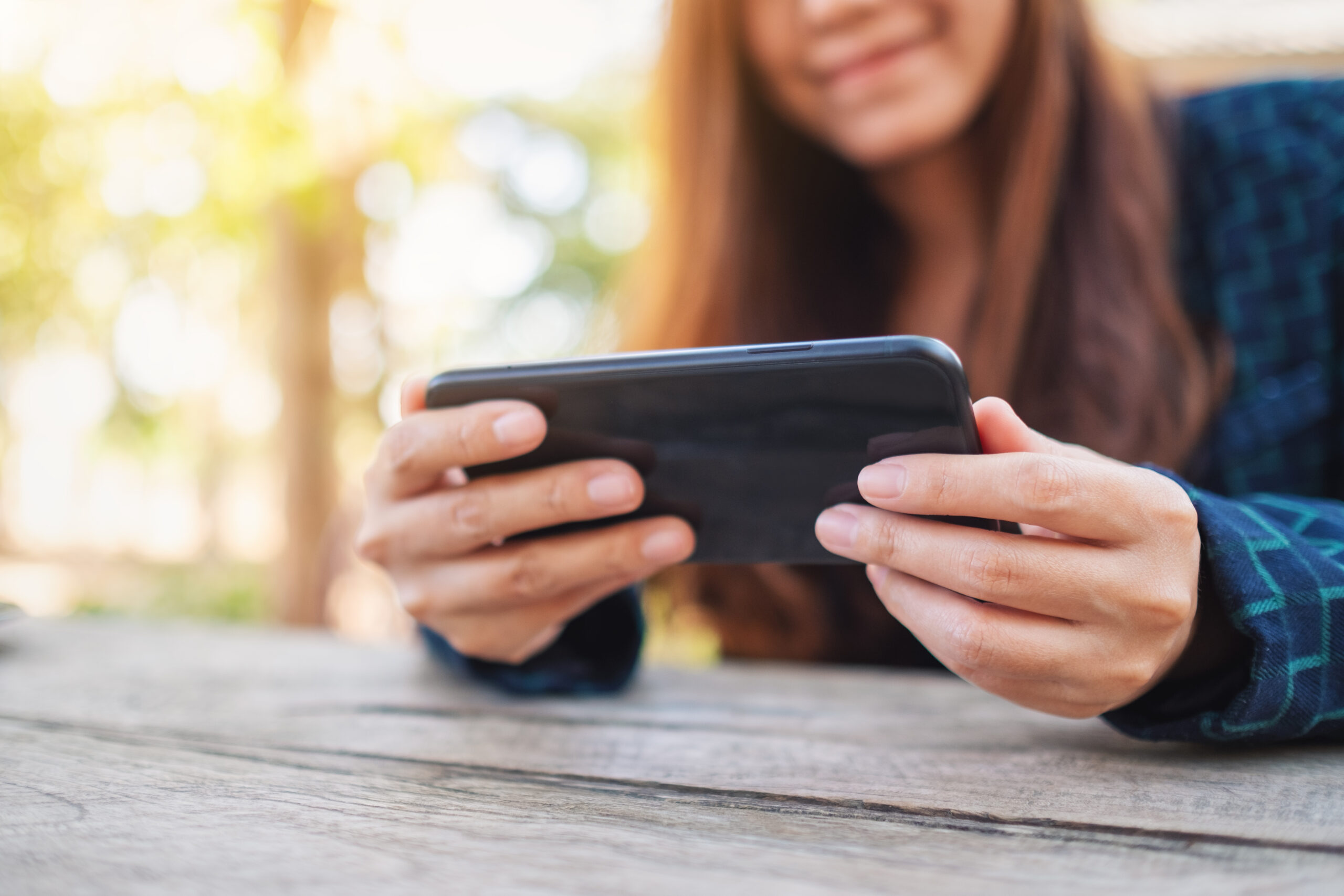 woman-enjoying-mobile-phone-outdoors-on-wooden-tab-2026-03-26-22-50-16-utc